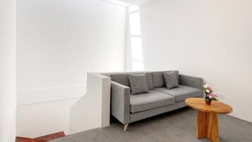 A modern living room with a grey sofa, a wooden coffee table, and a small vase of flowers.