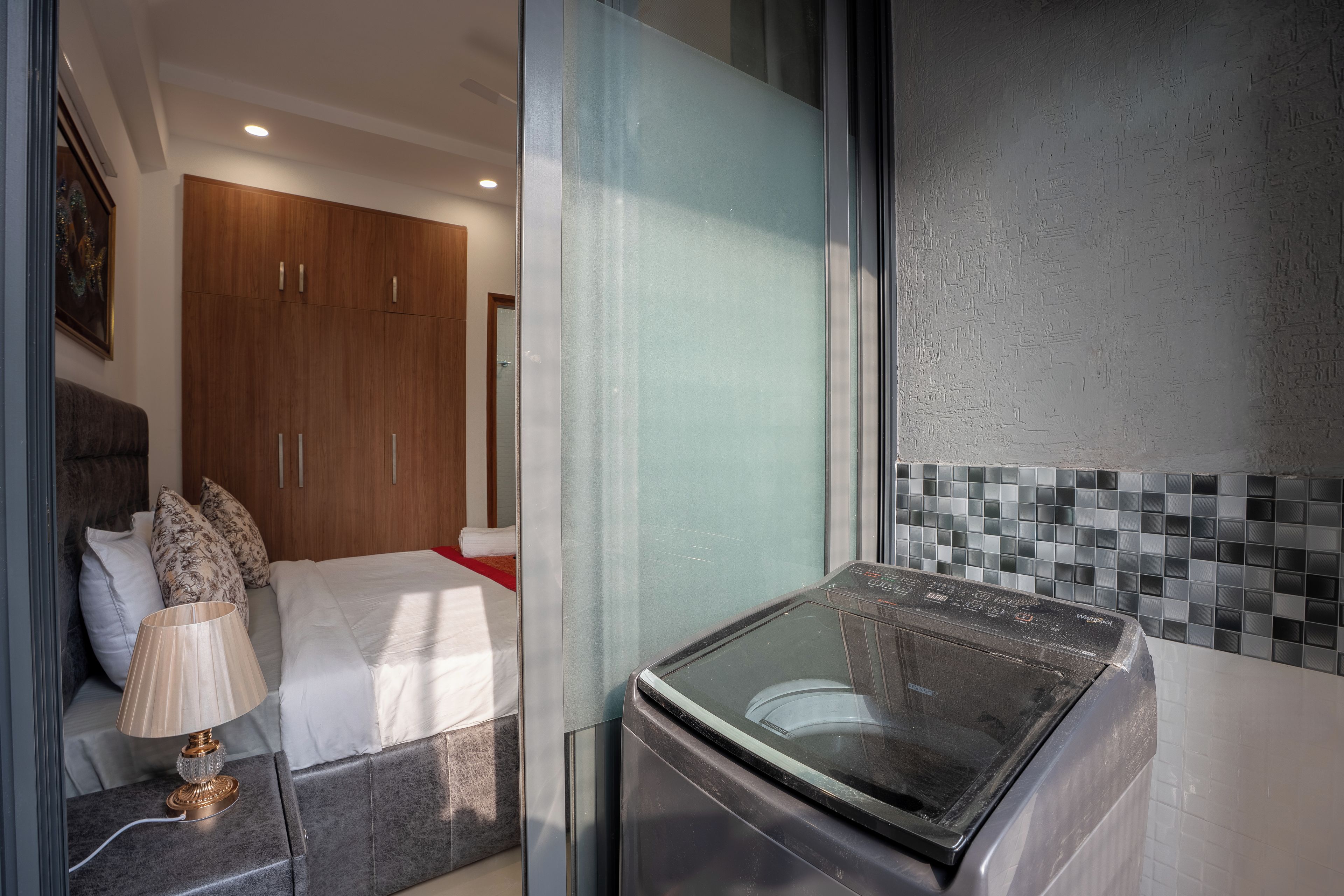 A hotel room with a bed, a nightstand, a washing machine, and a wardrobe.