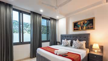Una moderna camera d'albergo con un letto grande, un comodino, una ventola a soffitto e un quadro appeso al muro.