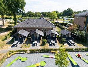 A building with multiple rooms, outdoor seating, and a parking area with golf carts. - Camping Cabin for 4 in Holland (Reutum)