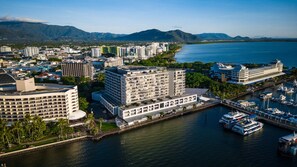 Eine Küstenstadt mit einer Marina, Hochhäusern und einer Bergkulisse im Hintergrund.