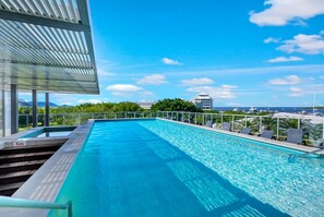Ein Pool auf dem Dach mit freiem Blick auf das Meer und entfernte Gebäude.