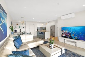 Ein modernes Wohnzimmer mit einer Couch, einem Couchtisch und einem großen Flachbildfernseher.