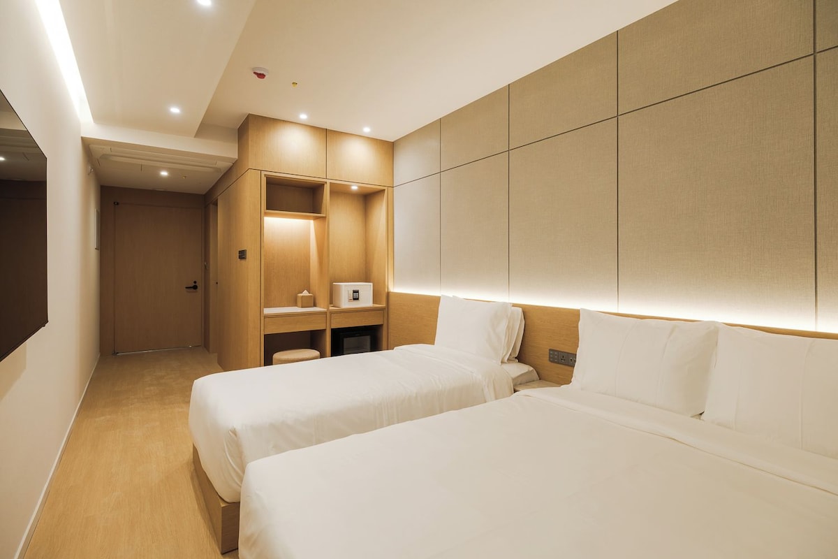 A hotel room with two beds, a minibar, a desk, and a wardrobe.