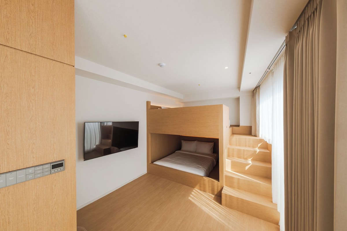 Una habitación moderna con literas, un televisor de pantalla plana y una escalera.