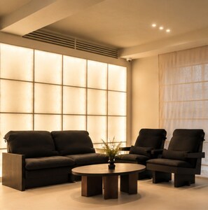 A modern living room with a sofa set, a coffee table, and a large window with blinds. - Nori Hotel (Seoul)