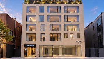 Un hôtel moderne avec une façade en verre, de nombreux étages et un jardin sur le toit.