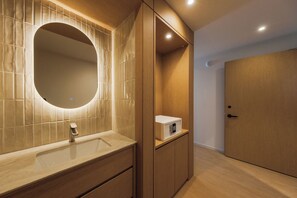 A modern bathroom with a vanity, a mirror, a toilet, and a shower area. - Nori Hotel (Seoul)