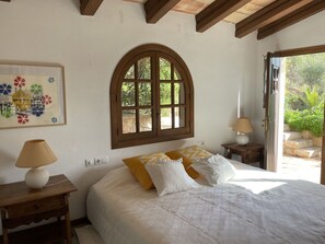 A bedroom with a large bed, a window, a lamp, and a painting on the wall. - "vista al Mar" Puerto Andratx (Andraitx)
