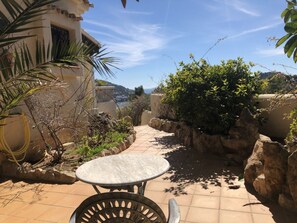 A patio area with a round table and chairs, surrounded by plants and a view of the sea. - "vista al Mar" Puerto Andratx (Andraitx)