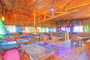 Un intérieur rustique avec des éléments en bois, un plafond haut, des meubles en bois et des rideaux colorés.