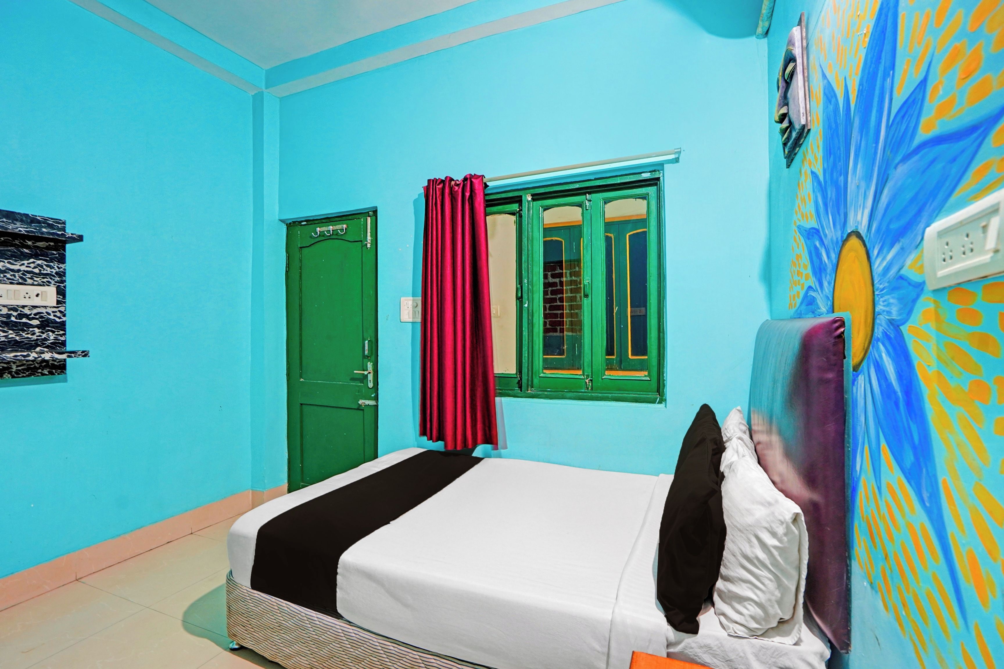 A room with a bed, a green door, and a window with red curtains.