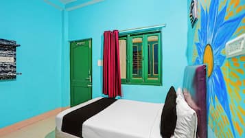 Una habitación con una cama, una puerta verde y una ventana con cortinas rojas.