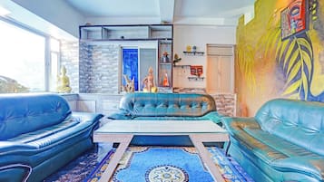 Una sala de estar con sofás de cuero azul, una mesa de centro, un tapete estampado y una pared de piedra.
