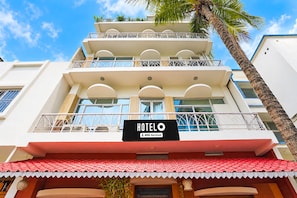 A hotel with a balcony, a sign indicating it is an 'Oyo-Serviced' hotel, and a red-tiled roof.