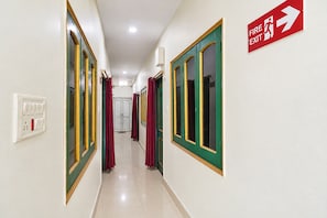 A corridor with doors, a fire exit sign, and a light switch.