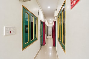 A corridor with doors, a fire exit sign, and a light switch.