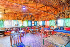 Un intérieur rustique avec des éléments en bois, un plafond haut, des meubles en bois et des rideaux colorés.