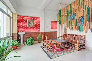 Una habitación con pared de ladrillo, un lavamanos, una mesa con sillas y un banco.