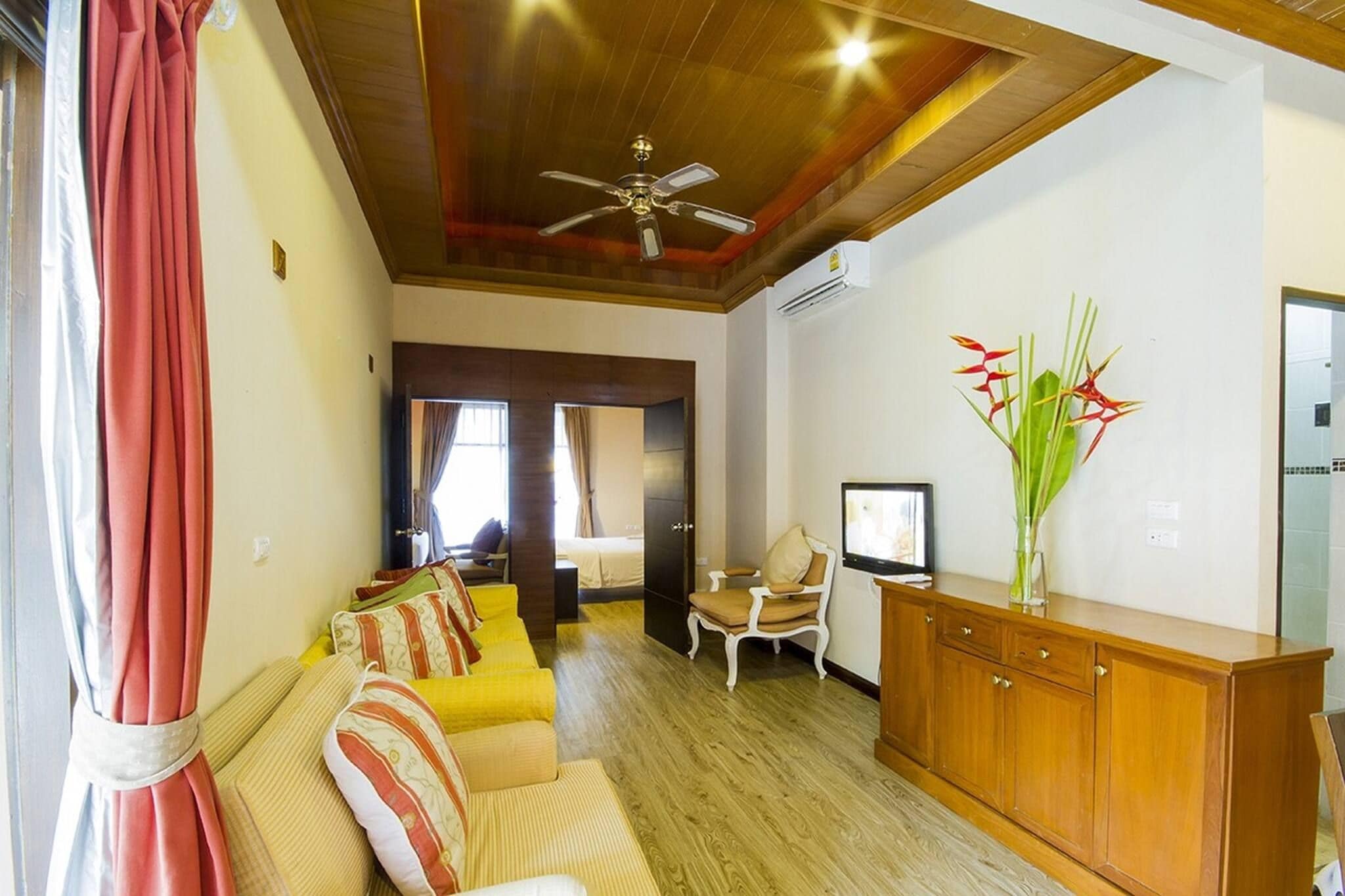 A living room with a sofa, a wooden cabinet, a television, and a ceiling fan.