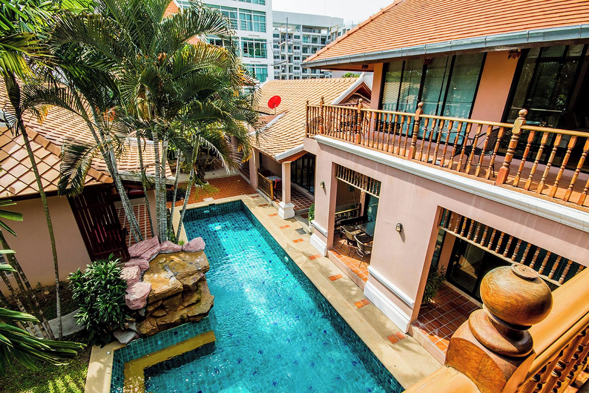 A residential building with a swimming pool, a balcony, and a view of the surrounding area.