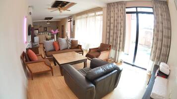 A modern living room with a sofa, chairs, a coffee table, and a dining area with a kitchen in the background.