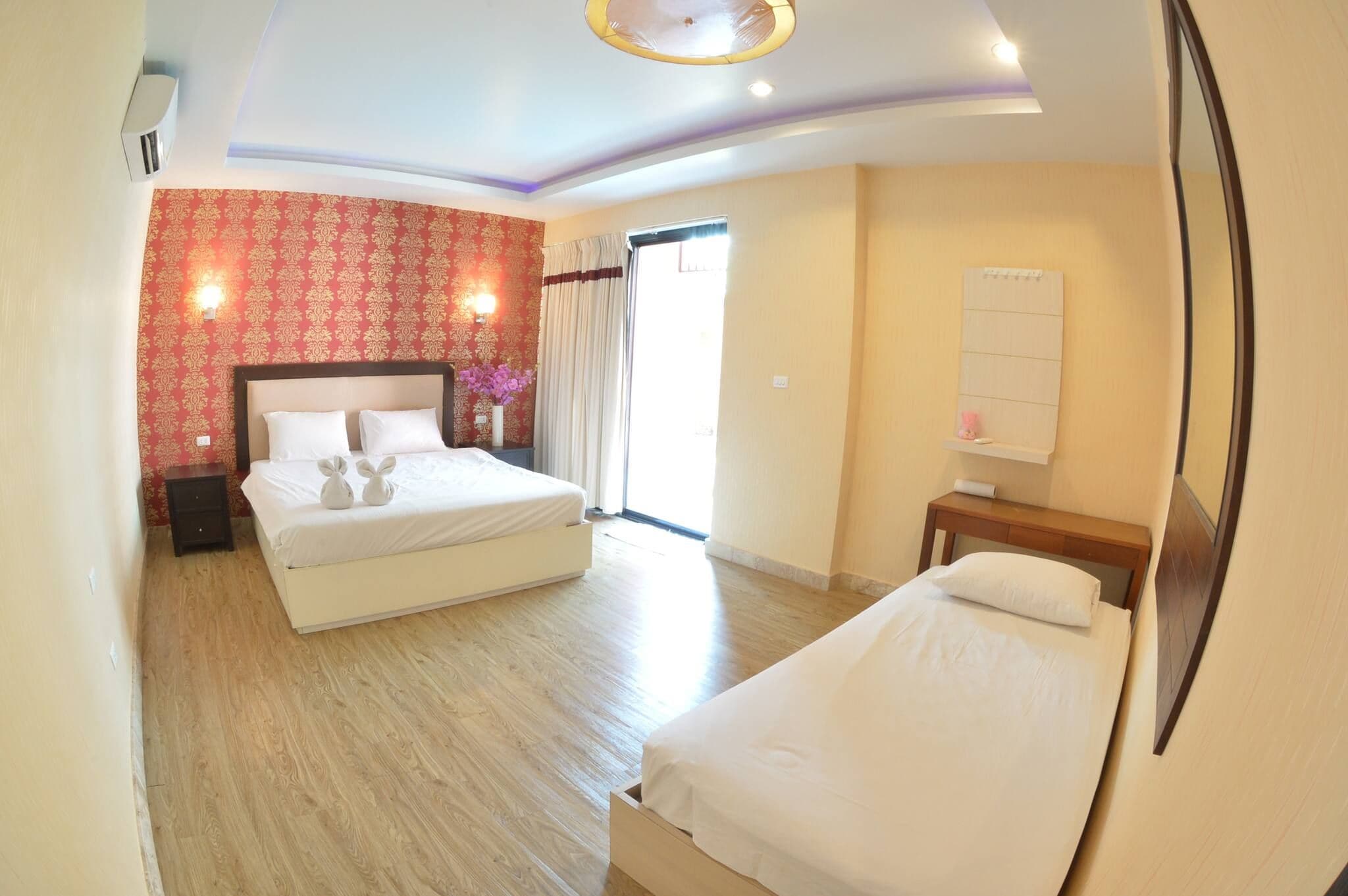 A hotel room with two beds, a large window, and a mirror on the wall.