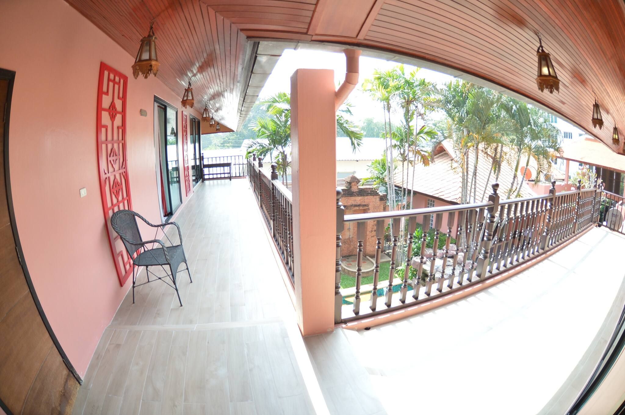 A balcony with a view of a garden and a building in the background.