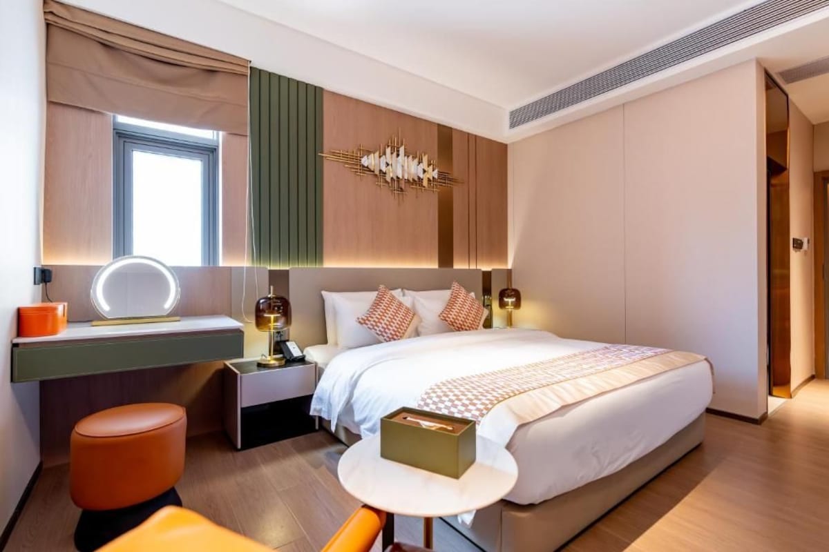 Habitació d'hotel moderna amb un llit gran, una taula de nit i un taulell de tocador amb un mirall.