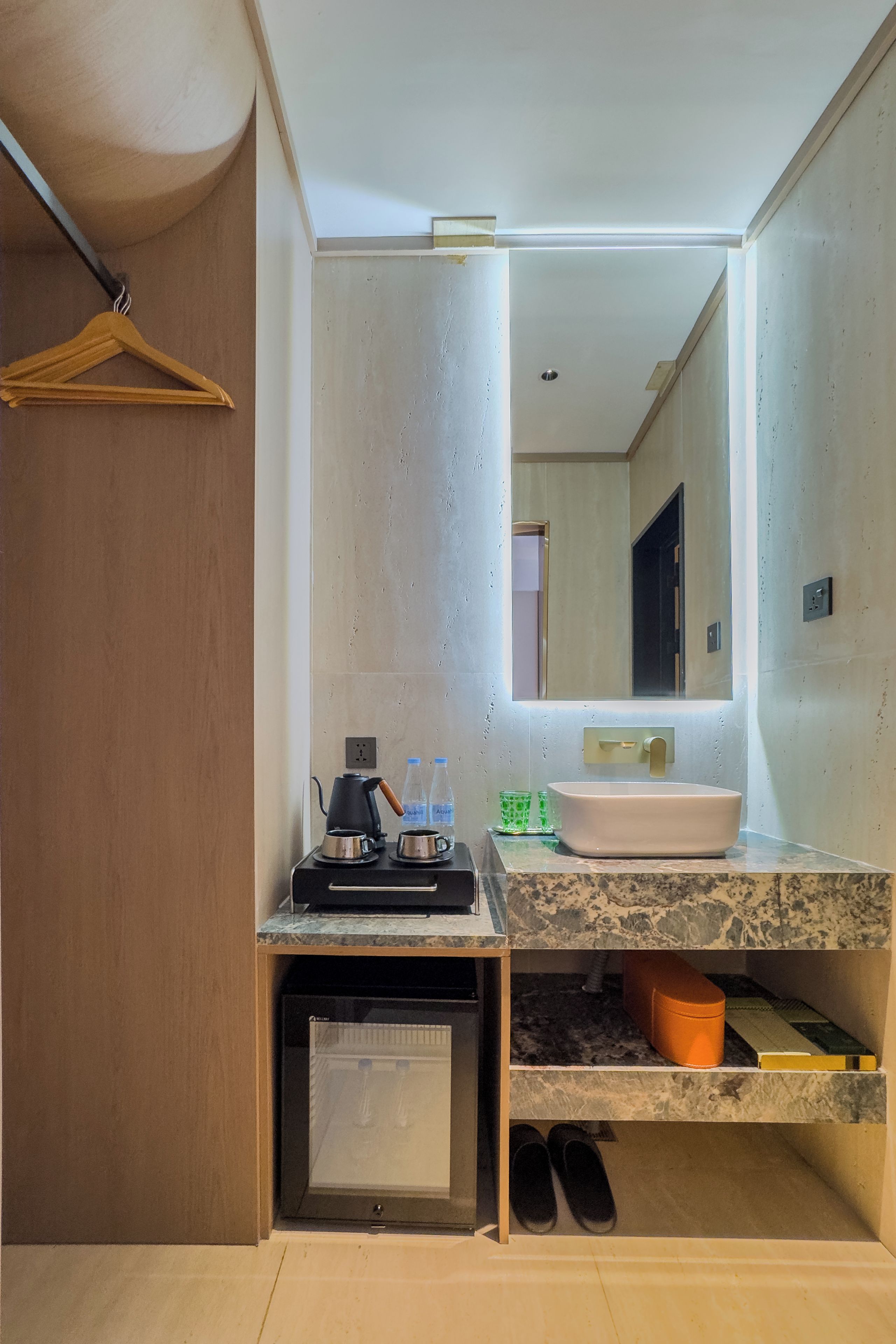 A modern bathroom with a sink, mirror, and a coffee maker.