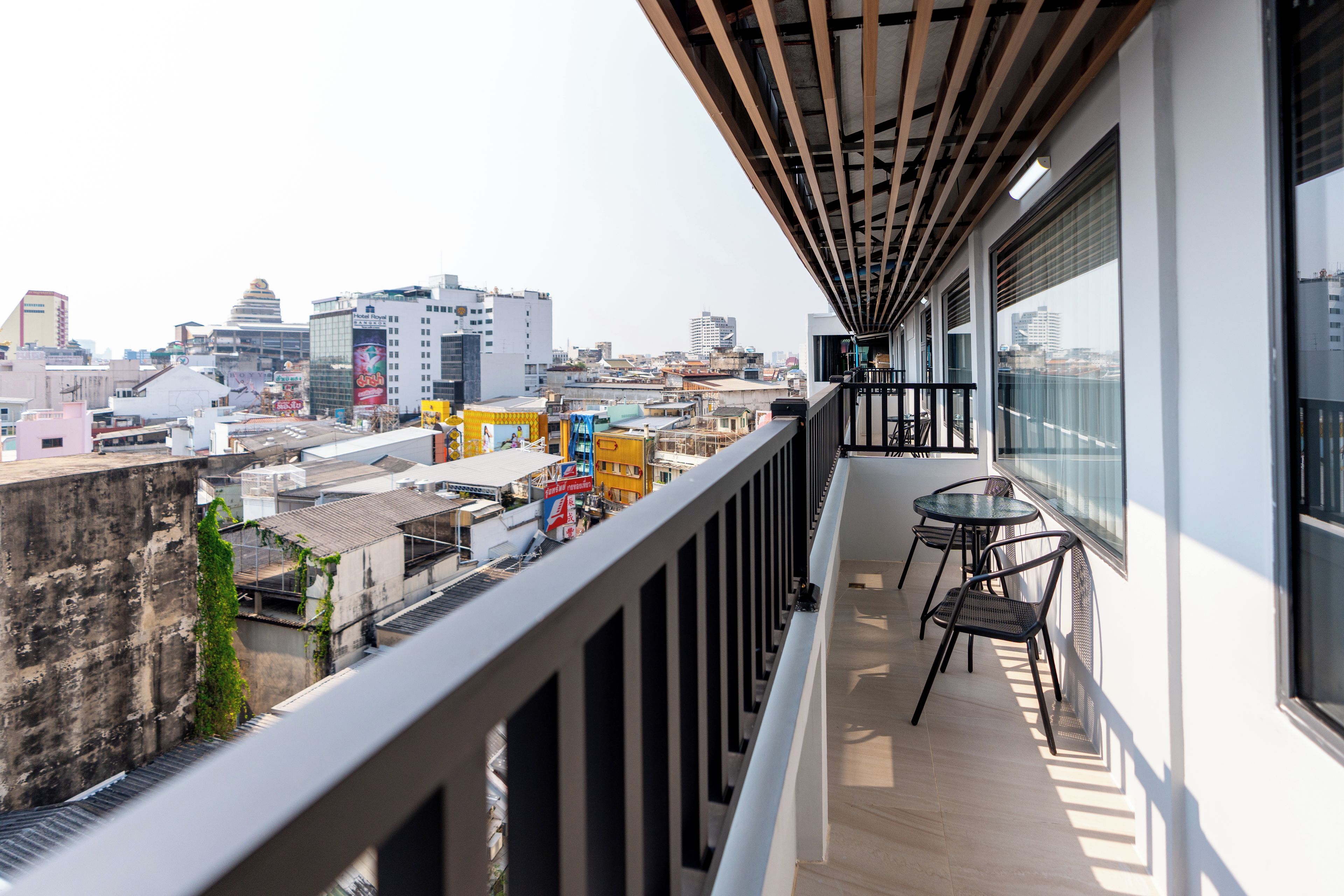 Ein Balkon mit Blick auf eine Stadtlandschaft, darunter Gebäude und ein klarer Himmel.