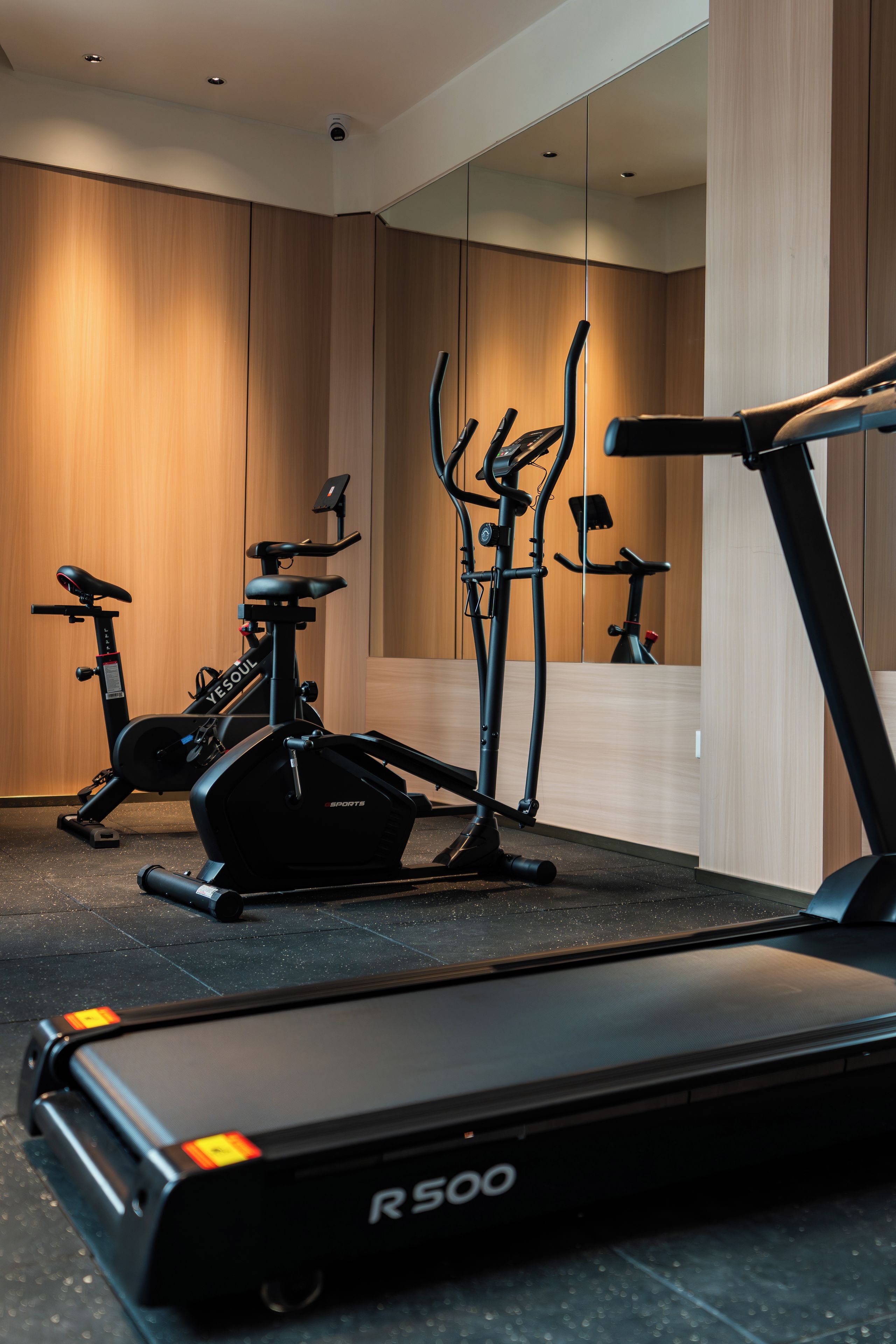 A gym with exercise equipment including a treadmill, elliptical, and stationary bike.