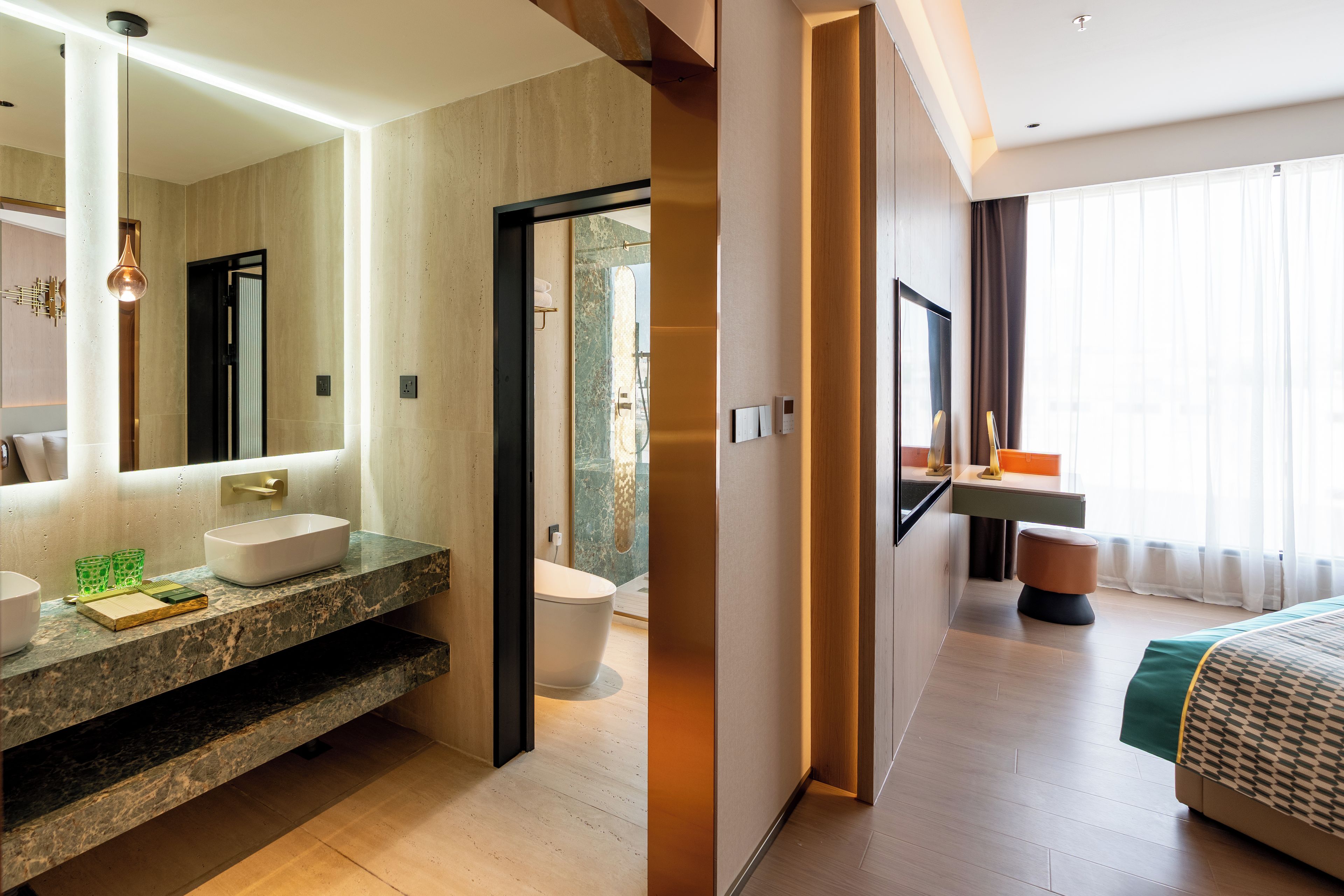 Un baño de hotel moderno con un espejo grande, un lavamanos y un inodoro.