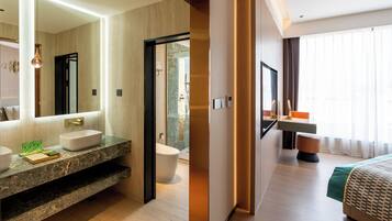 Un baño de hotel moderno con un espejo grande, un lavamanos y un inodoro.