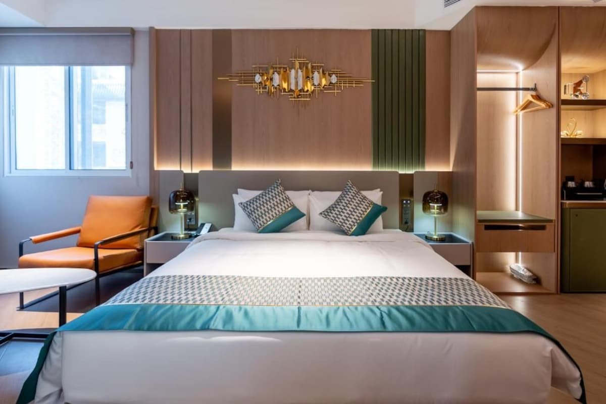 Habitació d'hotel amb un llit, una cadira, un escriptori i un armari.