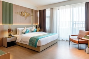 Habitación de hotel con una cama grande, mesitas de noche, una silla y vistas al exterior a través de cortinas translúcidas.