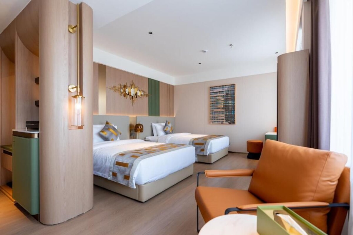 Habitació d'hotel amb dos llits, una zona de seients amb una cadira, un escriptori i una finestra gran.