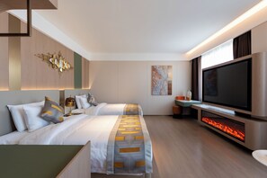 Een moderne hotelkamer met twee bedden, een grote flatscreen-tv, een open haard en een schilderij aan de muur.