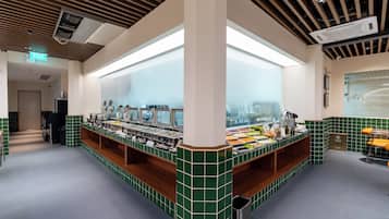 A buffet area with multiple food stations, a trash bin, and a seating area with chairs.