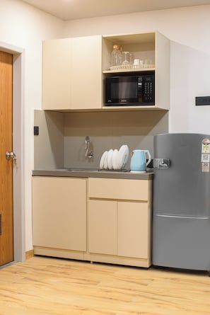 A compact kitchen with a microwave, a refrigerator, and a sink.