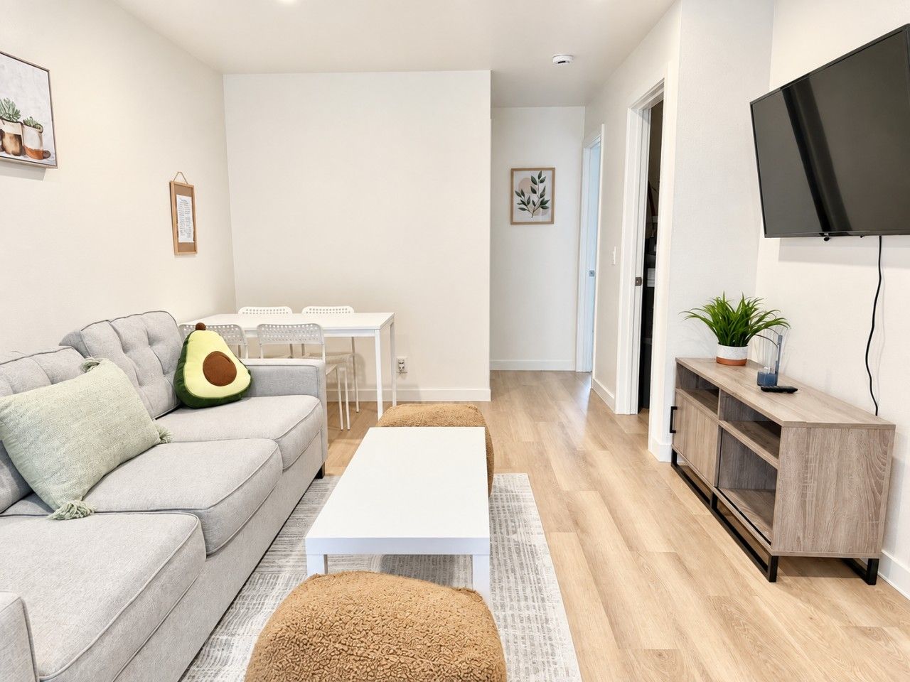 A modern living room with a grey sofa, white coffee table, and a TV on a wooden stand.