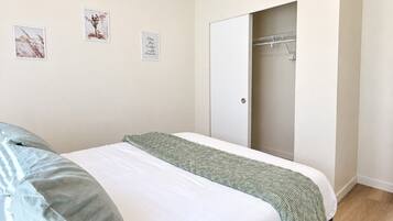 Un dormitorio con dos camas, un armario y una puerta que da a un baño.