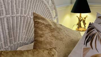 A wicker headboard with a lamp and decorative items on a bedside table.