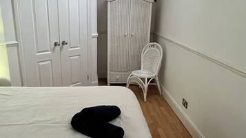 A bedroom with a bed, a wardrobe, a chair, and a skylight.