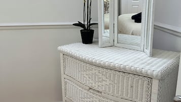 Een witte rieten dressoir met spiegel en een potorkidee.