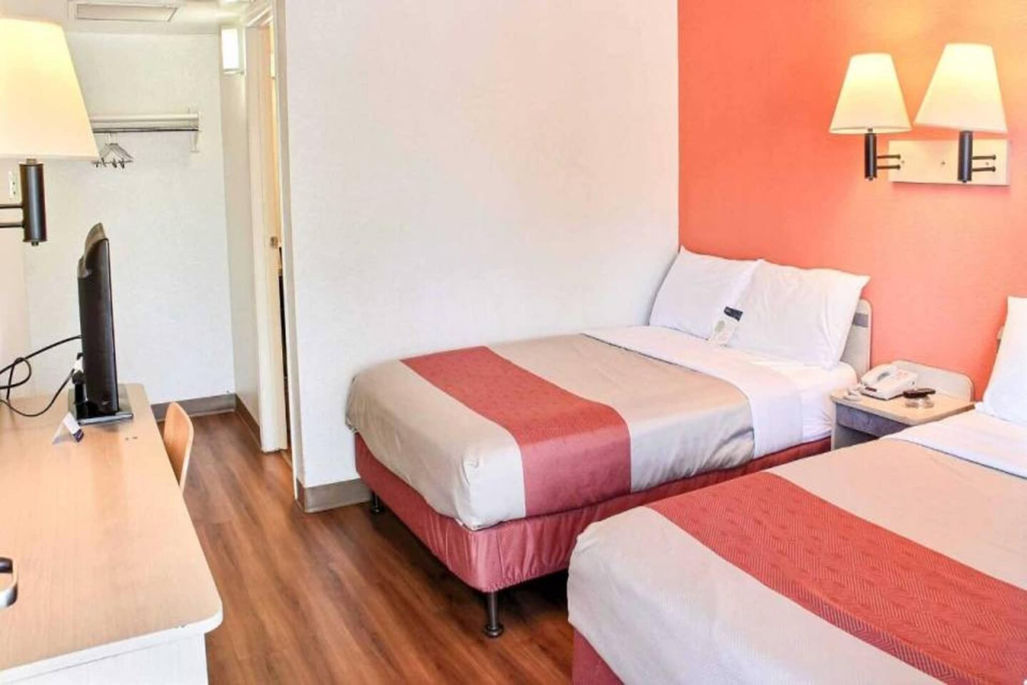 Una habitación de hotel con dos camas, un escritorio, una silla y un teléfono.