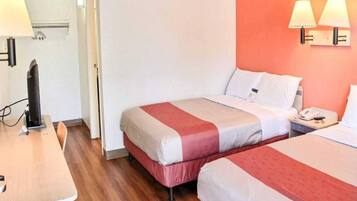 Una habitación de hotel con dos camas, un escritorio, una silla y un teléfono.