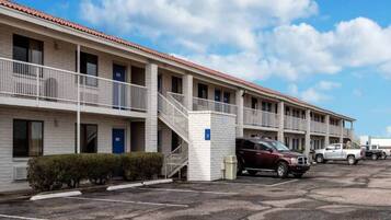 A motel with multiple rooms, a covered parking area, and a staircase leading to the entrance.