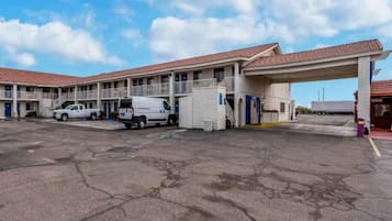 A motel with a parking lot, a covered entrance, and a building with a red-tiled roof.