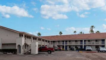 A motel with a parking lot, a red pickup truck, and a two-story building with a red-tiled roof.